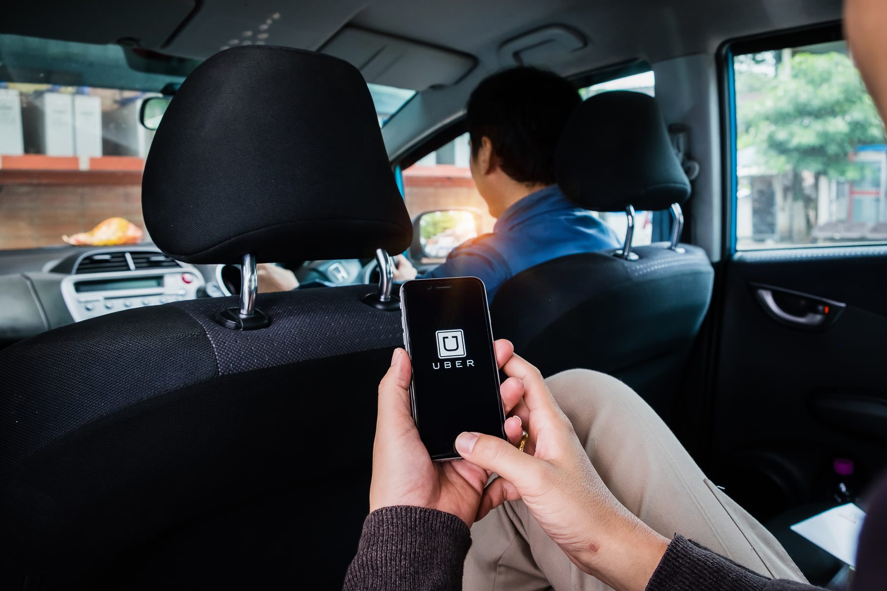 Man in backseat of car using Uber app